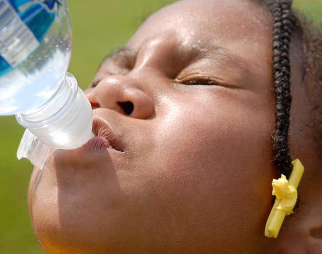 Child drinking water outdoors