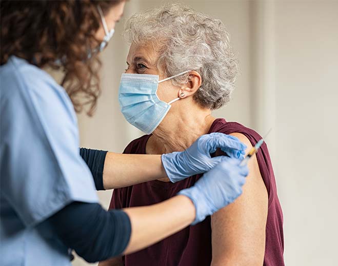 Clinician giving injection to older adult
