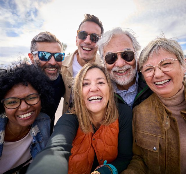Seis personas sonriendo y tomándose una selfie grupal juntas